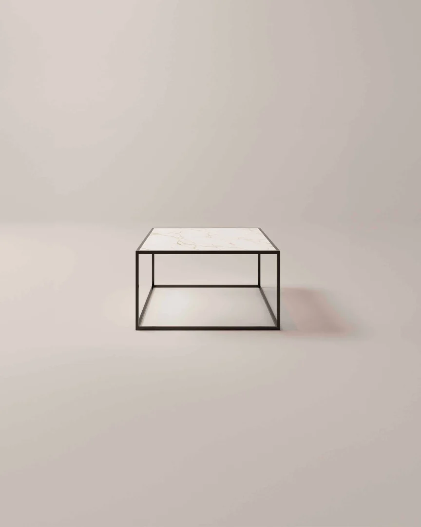 De Salontafel Zwart Design Tijdloos Design is een minimalistische vierkante salontafel met een wit marmeren blad en een dun zwart metalen frame, geplaatst tegen een effen lichtgekleurde achtergrond.