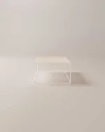 De Salontafel Compact Tijdloos Design is een minimalistische vierkante salontafel met een licht houten blad en heldere acryl zijkanten, perfect om elegantie toe te voegen aan een zacht verlichte, neutrale kamer.