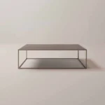 De Salontafel Brons van Roest Design is een minimalistische rechthoekige salontafel met een dun metalen frame, een plat houten blad en een open plank eronder, tegen een lichte achtergrond.