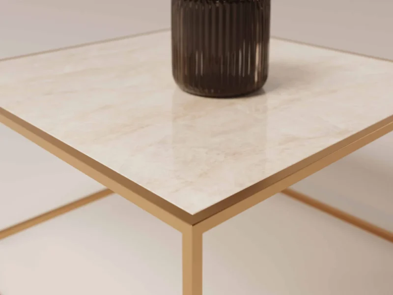 Een close-up van de Salontafel Messing Design, met een glanzend, marmerachtig vierkant blad en een goud metalen frame. Een donkere geribbelde vaas rust op het tafelblad tegen een neutrale, minimalistische achtergrond.
