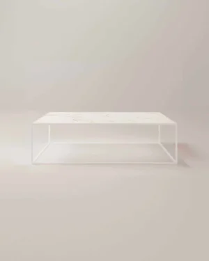 De Salontafel Roest van Wit Design is een minimalistische rechthoekige salontafel met een dun wit metalen frame en een wit marmeren blad, met strakke lijnen en een open, luchtig onderstel tegen een effen lichtgekleurde achtergrond.