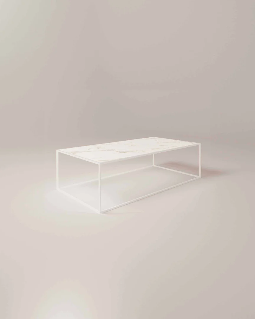De Salontafel Roest van Wit Design is een minimalistische rechthoekige salontafel met een dun wit metalen frame en een licht marmeren blad tegen een zachtbeige achtergrond.