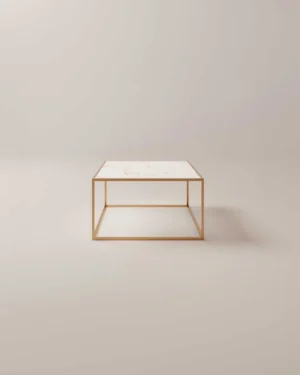 De Salontafel Messing Klassiek is een minimalistische vierkante salontafel met een dun goud metalen frame en een wit marmeren blad tegen een neutrale, lichtgekleurde achtergrond.
