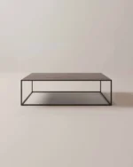 De Salontafel Zwart, Roest Rond is een minimalistische salontafel met een donker metalen frame en een plat houten blad, met een open doosachtig ontwerp. Afgebeeld tegen een effen lichte achtergrond.