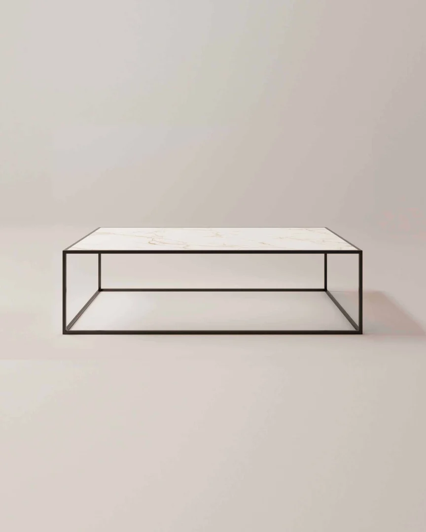 De Salontafel Zwart Design is een minimalistische rechthoekige salontafel met een slank zwart metalen frame en een wit marmeren blad tegen een effen lichtgekleurde achtergrond.