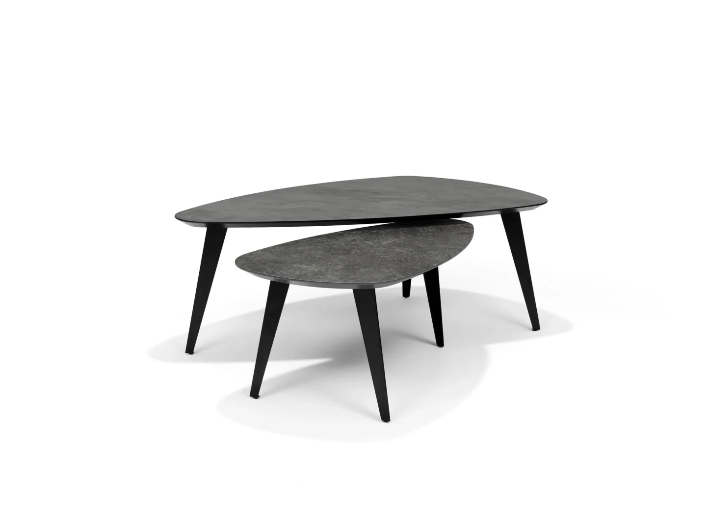 De Salontafel 130 x 70 CM Rechthoek Keramiek bestaat uit twee moderne zwarte nesttafels met rechthoekige keramische bladen en schuine poten, tegen een effen witte achtergrond. De kleinere tafel is gedeeltelijk weggestopt onder de grotere.