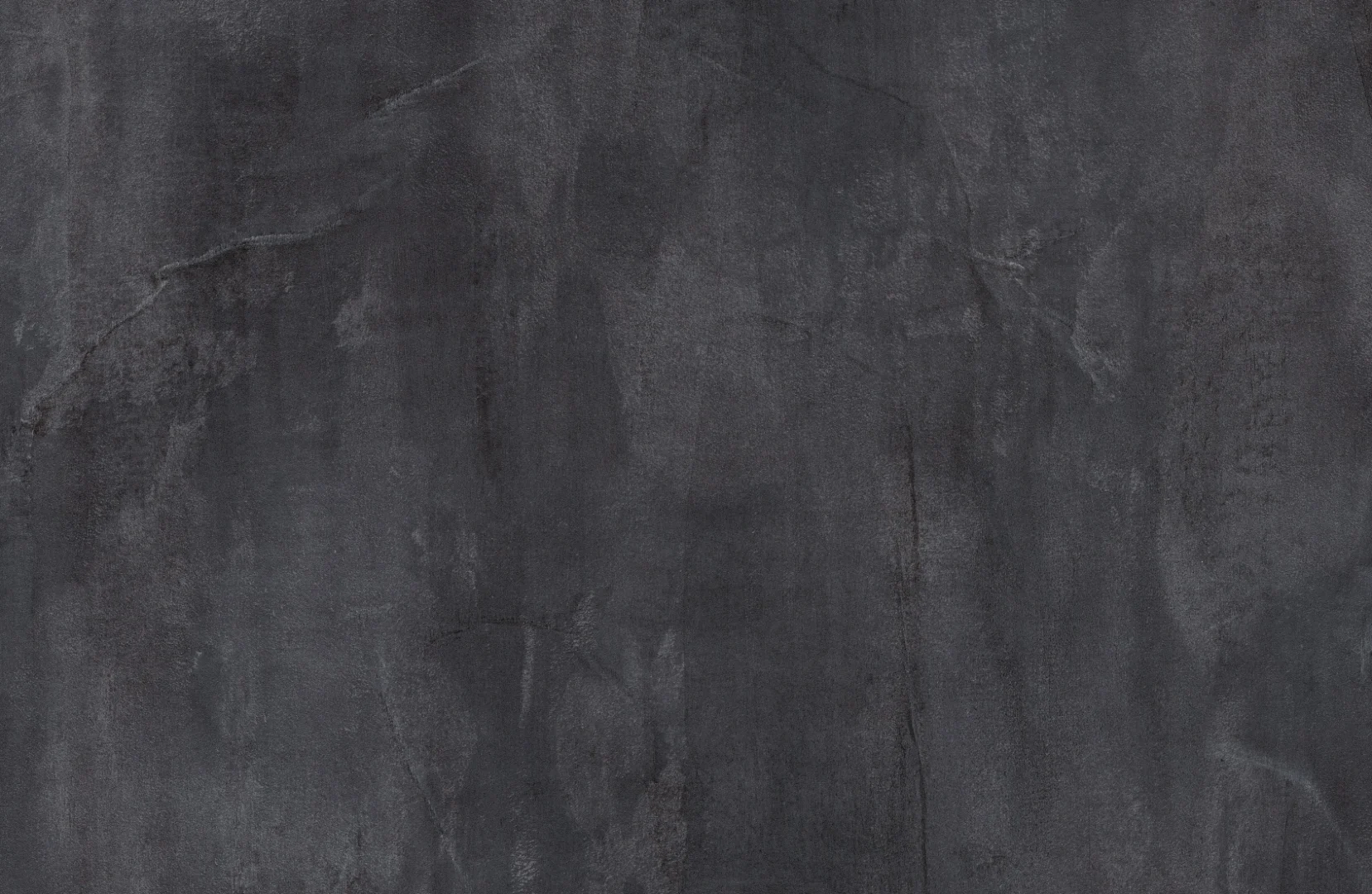 De Salontafel Grijs 130 x 70 CM MDF heeft een donkergrijs structuuroppervlak met subtiele schaduwvariaties die lijken op beton of leisteen en bevat overal vage lijnen, vegen en natuurlijk ogende imperfecties.