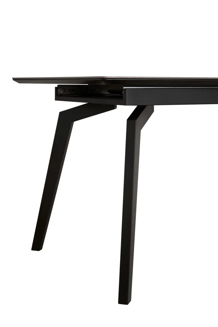 Een close-up van de Venus Uitschuiftafel 160x90 (+1 x 40cm) Deckstone Zwart Marmer, met een modern zwart marmeren tafelblad, schuine poten en een gedeeltelijk zichtbaar uitschuifmechanisme, tegen een witte achtergrond.