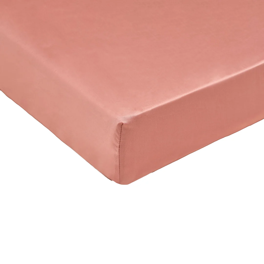 Detailopname van een terraroze hoeslaken van tencel satijn. De stof heeft een subtiele glans en is strak om een matras gespannen.