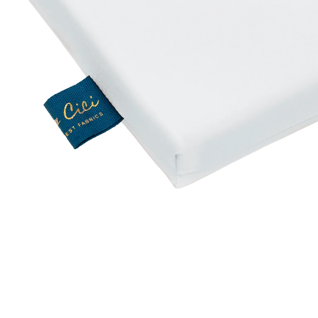 Detailopname van een wit dekbedovertrek met een blauw label. Het label heeft gouden letters. De stof lijkt zacht en glad.