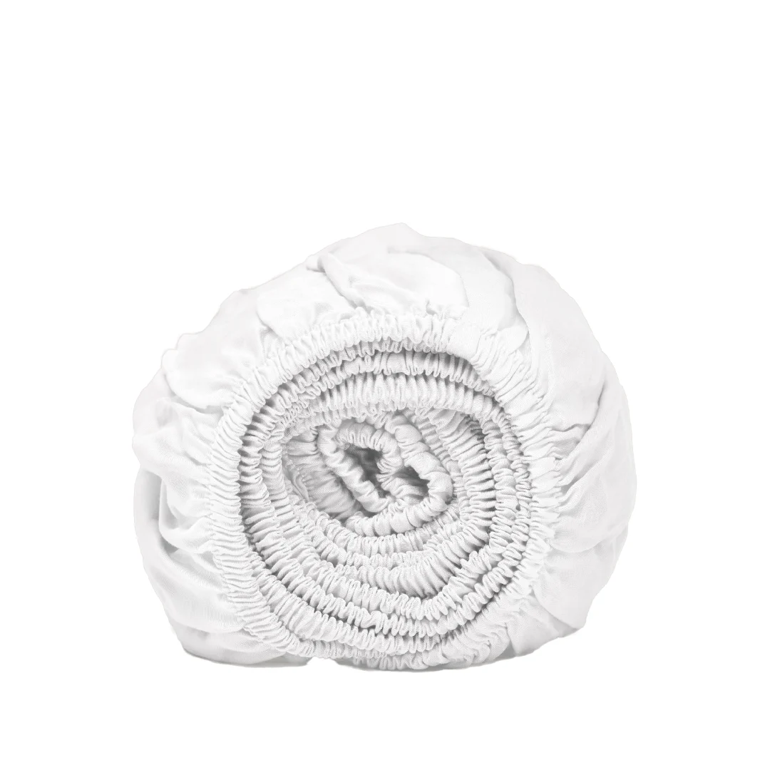 Opgerold wit hoeslaken van Tencel™ Lyocell, close-up. Zachte stof met elastiek, studiofotografie tegen een witte achtergrond.