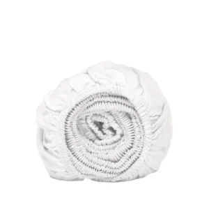Opgerold wit hoeslaken van Tencel™ satijn, zachte stof met elastiek, close-up op een witte achtergrond. Ademend en koel.