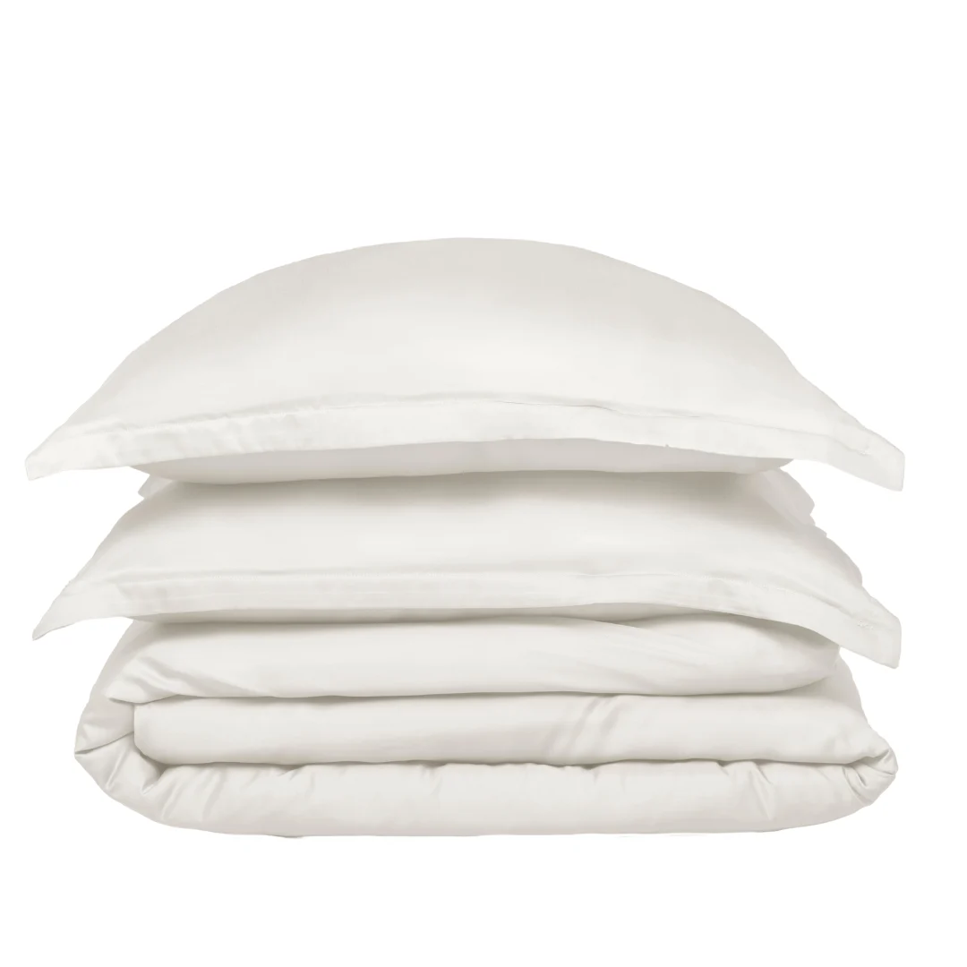 Een netjes gestapelde Dekbedovertrek 200x220 Makkelijk combineren set: een kussen bovenop, opgevouwen laken in het midden en een dekbed onderaan, allemaal tegen een effen witte achtergrond.