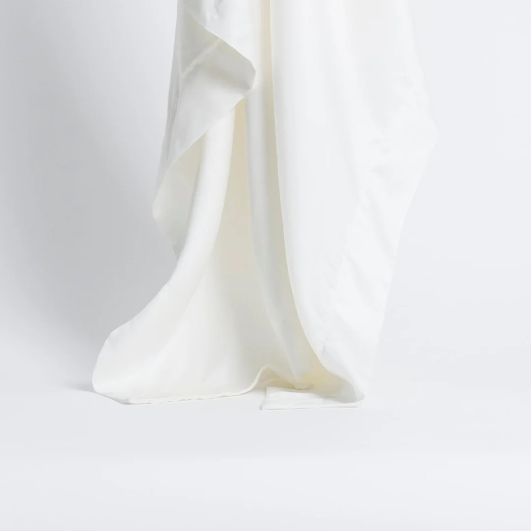 De Dekbedovertrek 200x220 Makkelijk combineren heeft een witte, zijdeachtige stof die elegant drapeert met zachte plooien en een gladde, vloeiende textuur tegen een effen witte achtergrond.