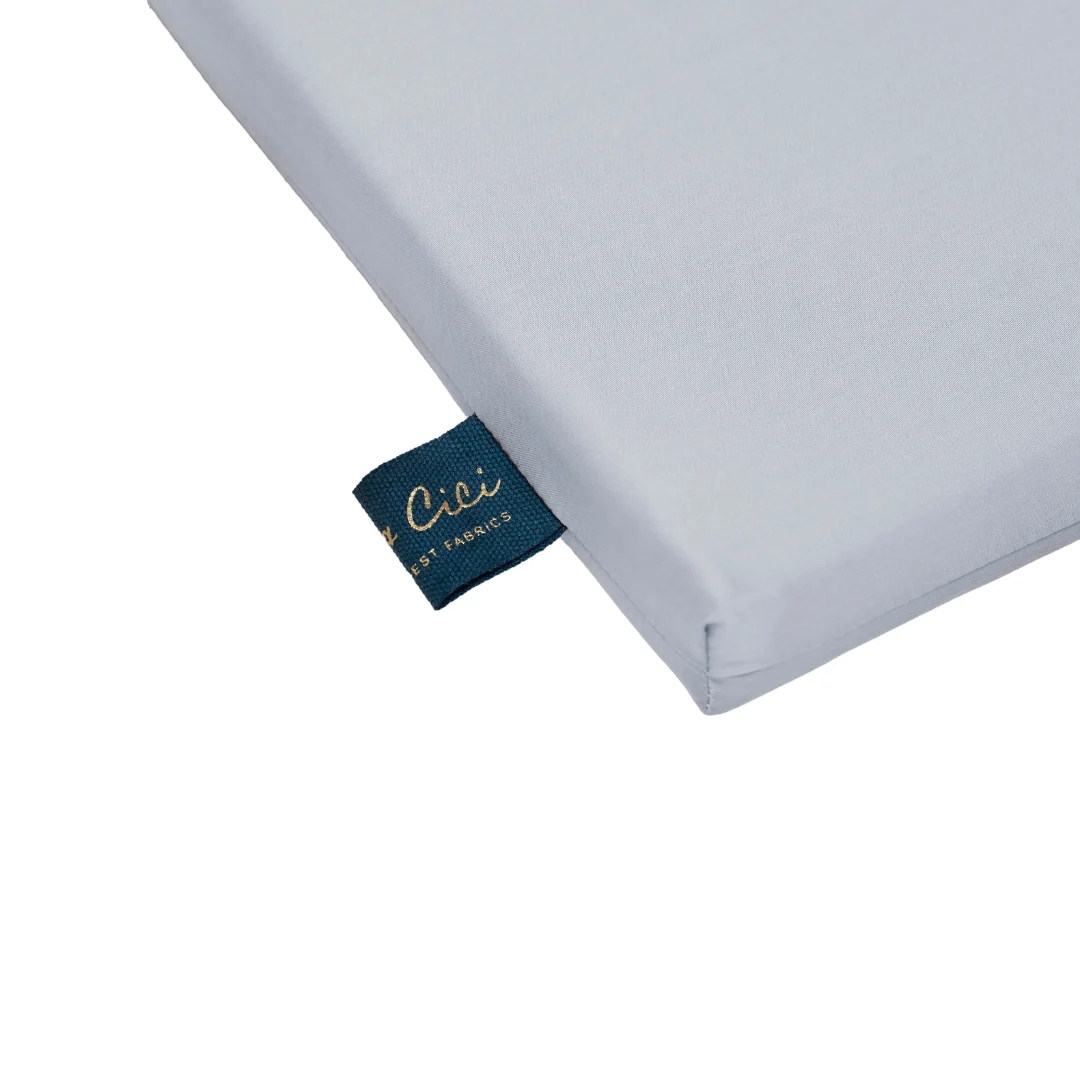 Een close-up van de hoek van een lichtgrijze Dekbedovertrek 200x220 Plantaardig met materiaal, met een blauw stoffen label met gouden tekst.