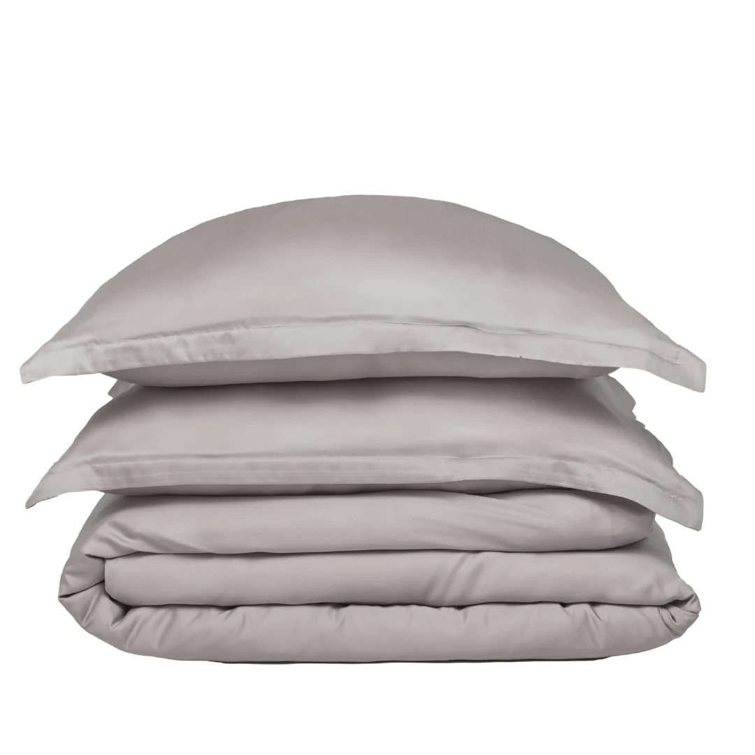 Grijze dekbedovertrek set, zachte weving. Stapel van kussenslopen en dekbedovertrek, close-up. Neutrale achtergrond, zachte belichting.