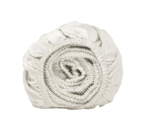 Oprol van wit hoeslaken, close-up. Elastische randen zichtbaar. Zachte belichting, effen witte achtergrond. Tencel Lyocell materiaal.