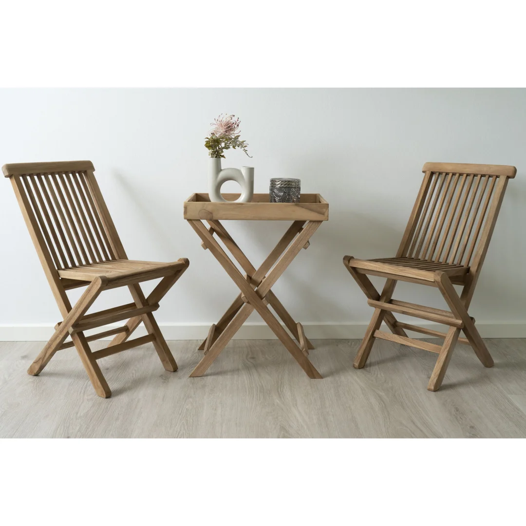 De Ronda Teak Dienbladtafel (29x39x49,5 cm) staat met twee houten klapstoelen op een lichte vloer. Op de tafel staan een witte vaas met bloemen en twee decorstukken tegen een effen witte muur.