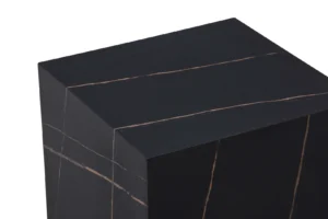 Een close-up van de bovenste hoek van de Bijzettafel Zwart MDF, een zwarte rechthoekige bijzettafel met dunne, lichtgekleurde diagonale aders over het oppervlak voor een gepolijste marmerachtige uitstraling, tegen een witte achtergrond.