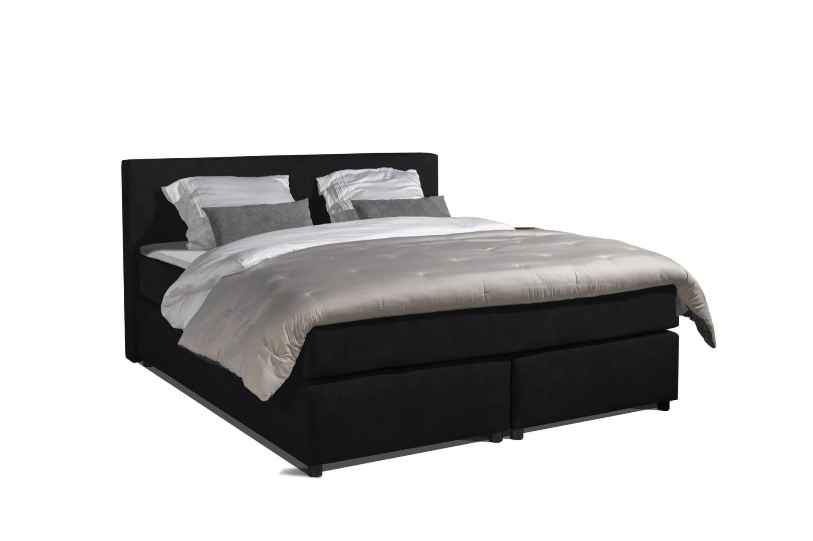 Zwarte boxspring met topper, gezien vanuit een hoek. Zachte belichting toont de stof en de kussens op het bed. Neutrale achtergrond.