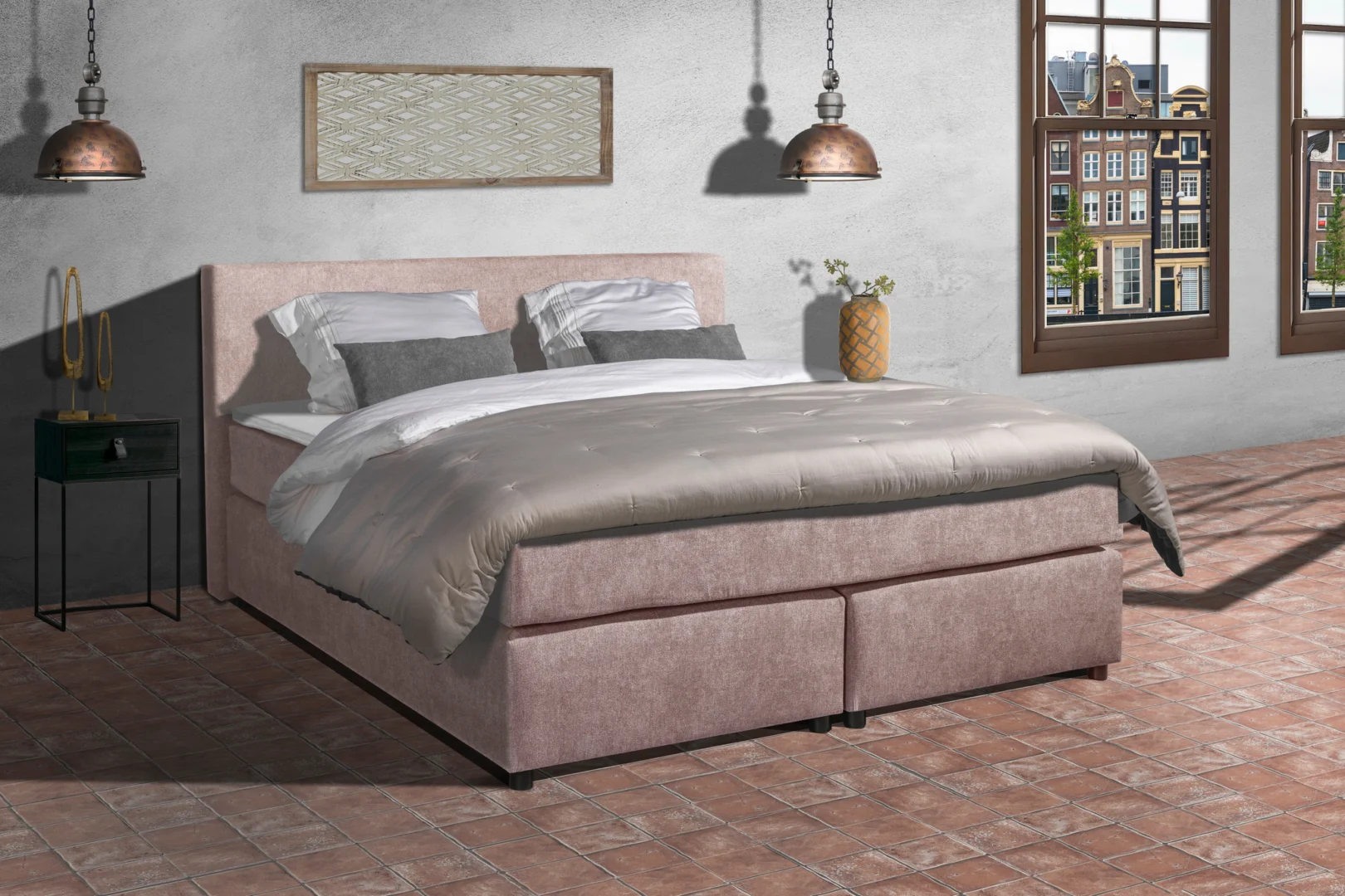 Roze stoffen boxspring met pocketvering en grijze dekbedovertrek. Interieur met bakstenen vloer en Amsterdams uitzicht door het raam.