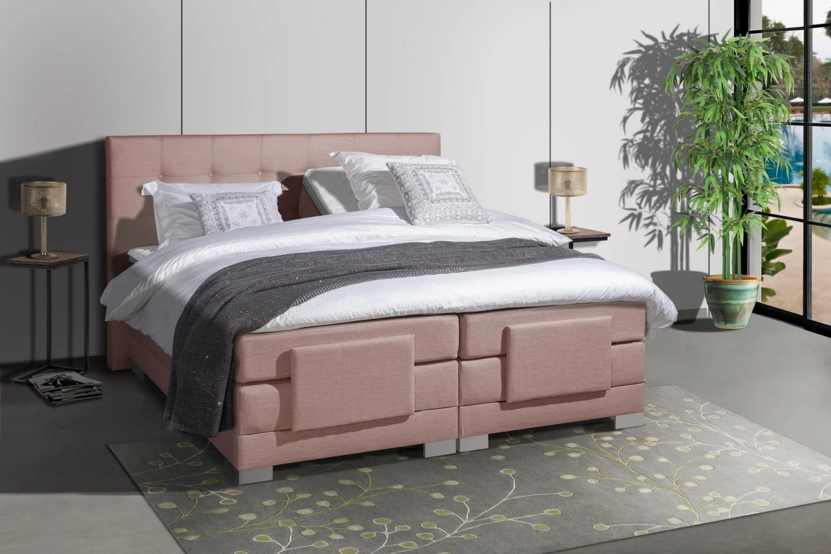 Roze houten boxspring met wit beddengoed en grijze sprei, gezien vanuit een laag standpunt. Kamerplant en vloerkleed in de slaapkamer.
