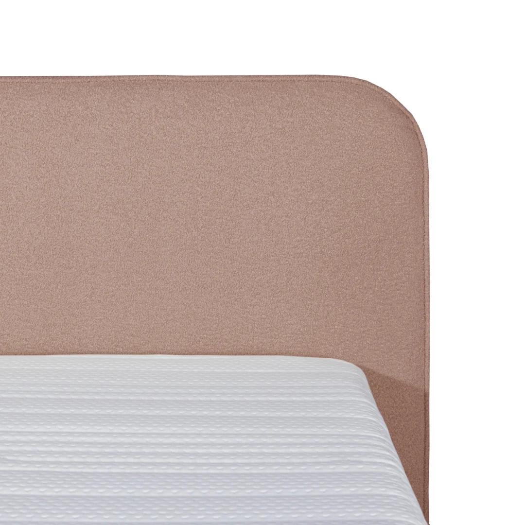 Detailopname van een oud roze bouclé boxspring met pocketvering matras en afgeronde hoeken tegen een witte achtergrond.
