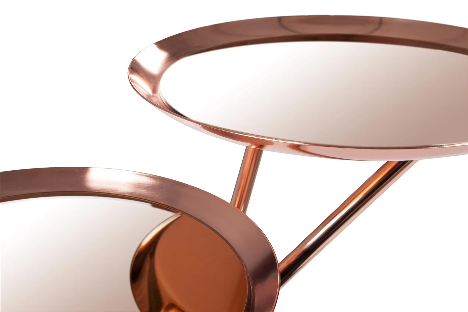 Close-up van twee ronde Bijzettafel Goud, Roze Ijzer Chique dienbladen met koperkleurige spiegeloppervlakken, verbonden door schuine stangen, tegen een witte achtergrond.