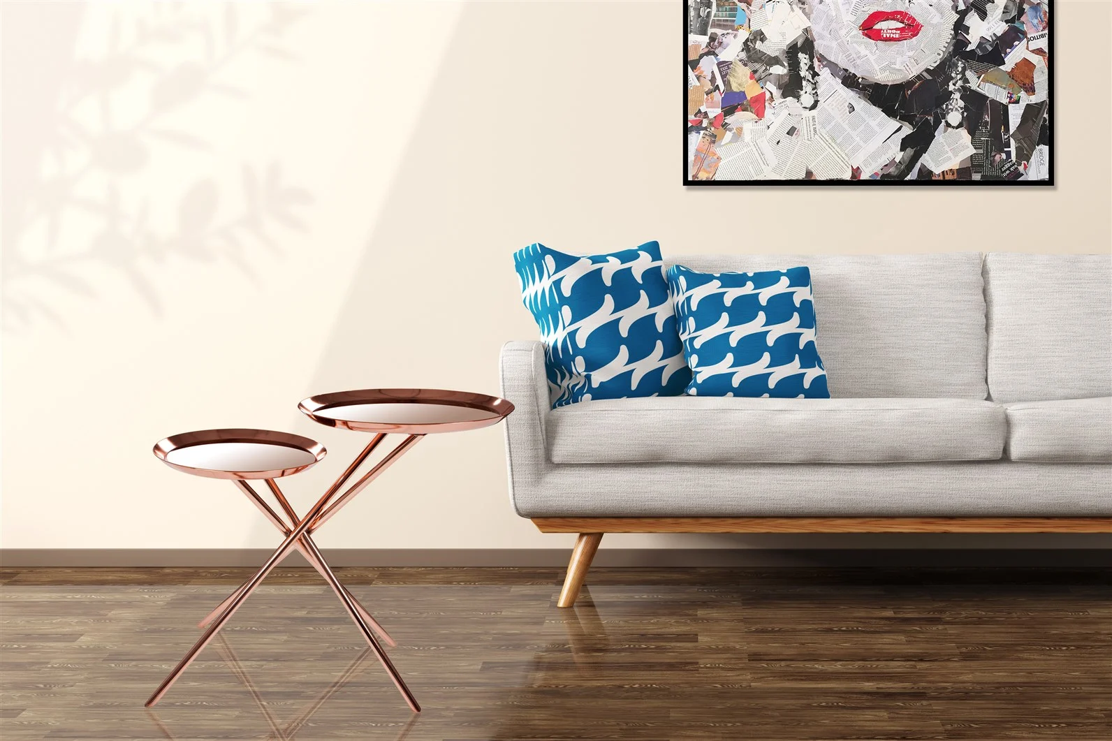 Een moderne woonkamer met een lichtgrijze bank, twee kussens met blauw en wit patroon, houten vloer, crèmekleurige muur, een abstract ingelijst kunstwerk boven de bank en een paar metalen bijzettafeltjes van Bijzettafel Goud, Roze Ijzer Chique.