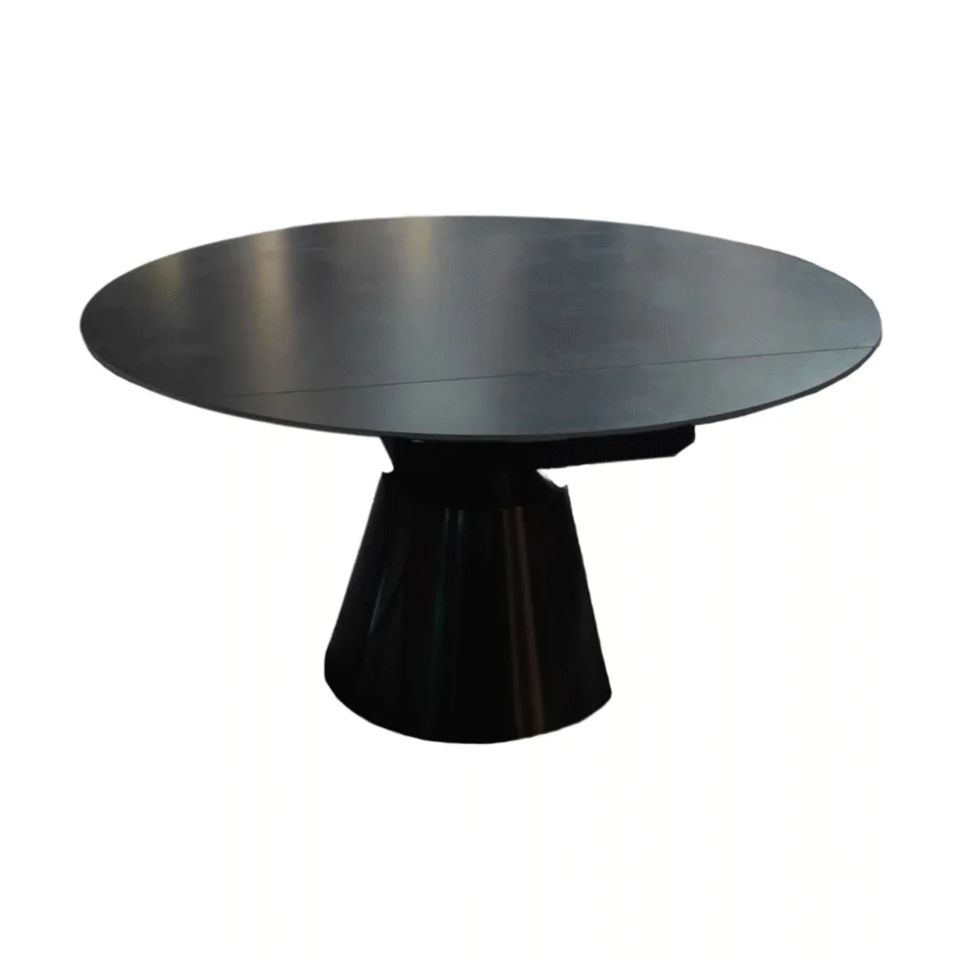 De DRAAI DT ZWART 135/86X75 eettafel heeft een rond, modern ontwerp in donkergrijs sintersteen met een breed, stevig voetstuk, afgebeeld tegen een effen witte achtergrond.