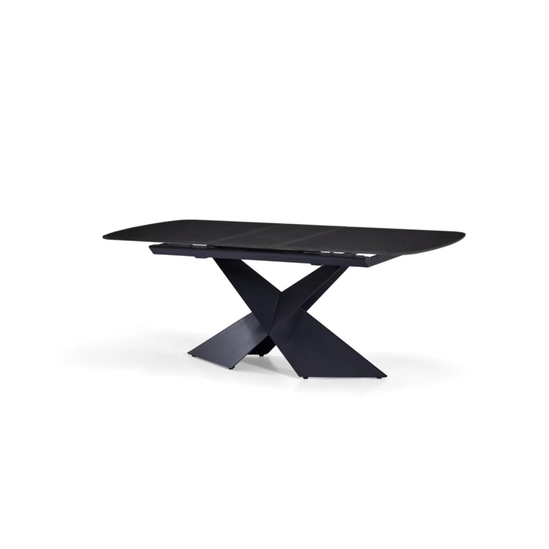 De DONKERGRIJZE SINTEERSTEEN EMPIRE SY8910 DT 180/220X90 is een moderne donkergrijze rechthoekige eettafel met afgeronde hoeken en een kruisend X-vormig onderstel, afgebeeld tegen een effen witte achtergrond.