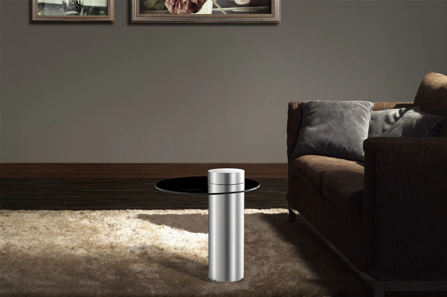 Een moderne woonkamer met een bruine bank, grijze kussens, een beige vloerkleed, Bijzettafel Zilver (een compacte, strakke ronde metalen bijzettafel) en twee ingelijste kunstwerken op een grijze muur.