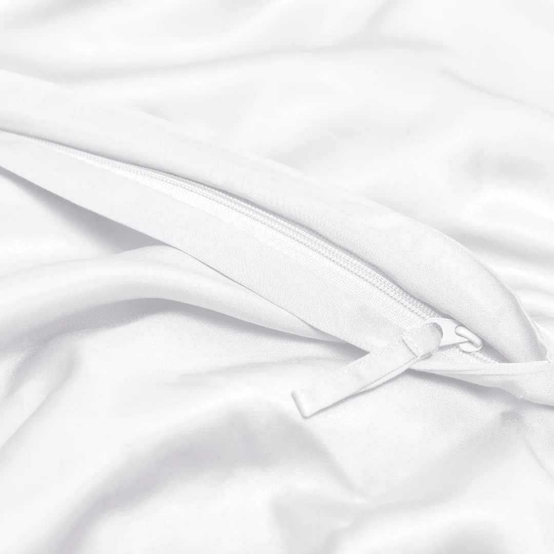 Close-up van de Dekbedovertrek 140x220 Wit Snelle upgrade: een witte rits gedeeltelijk gesloten op gladde witte stof met zachte plooien, die de kwaliteit en subtiele details van het beddengoed benadrukken.