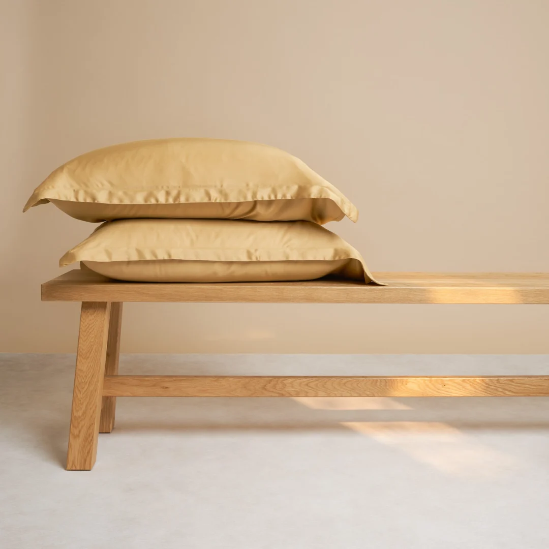 De Dekbedovertrek 60x70 Geel Dagelijks comfort staat op een lichte houten bank met een neutrale beige muur en lichtgekleurde vloer op de achtergrond.