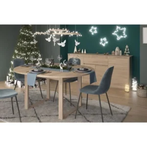 Een moderne eetkamer met het BETTY-buffet en de uitschuifbare ronde tafel van PARISOT in eikenhout, blauwfluwelen stoelen, een kerstboom met lichtjes, feestelijke decoraties en een houten dressoir versierd met kerstornamenten voor een gezellige, elegante sfeer.