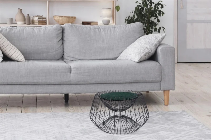 Een moderne woonkamer met een lichtgrijze bank, twee gedessineerde kussens, een Bijzettafel Zwart, Groen 37 CM Rond Marmer, een gedessineerd vloerkleed en een bladplant op de achtergrond.