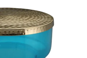 Een close-up van de Bijzettafel Blauw, met een gestructureerd gouden metalen deksel en een doorschijnend blauw rond lichaam, tegen een witte achtergrond.