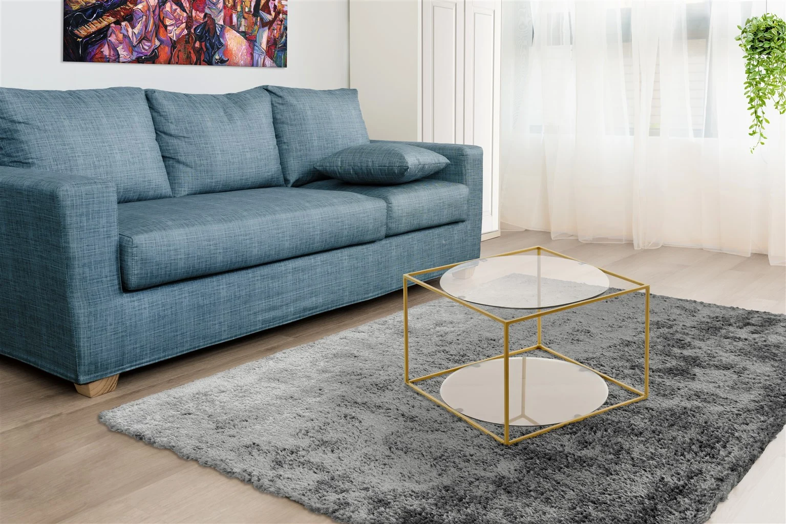 Een moderne woonkamer met een blauwe bank, een Bijzettafel Grijs, Goud Rond Metaal salontafel, een grijs vloerkleed, een kleurrijk schilderij aan de muur, transparante gordijnen en een hangende groene plant in de hoek.