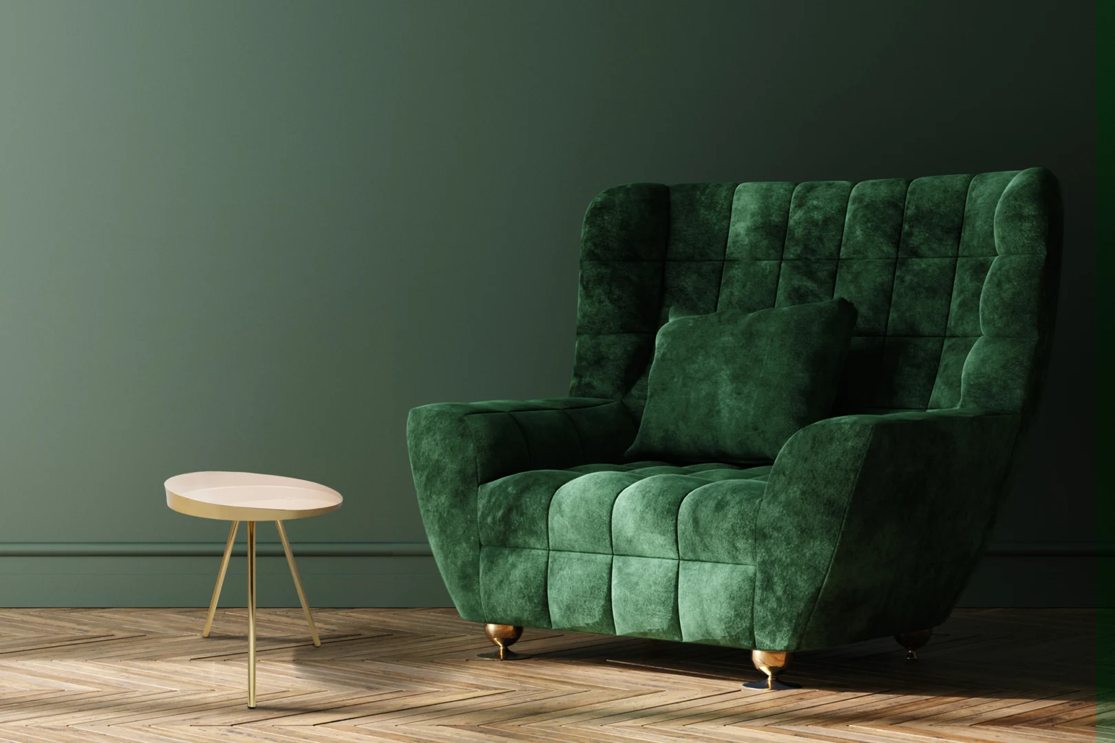 Een pluche, donkergroene fluwelen fauteuil met een bijpassend kussen staat naast de Bijzettafel Ivoor Rond Ijzer Design, een lichtgekleurde ronde bijzettafel, op een houten visgraatvloer tegen een matgroene muur.