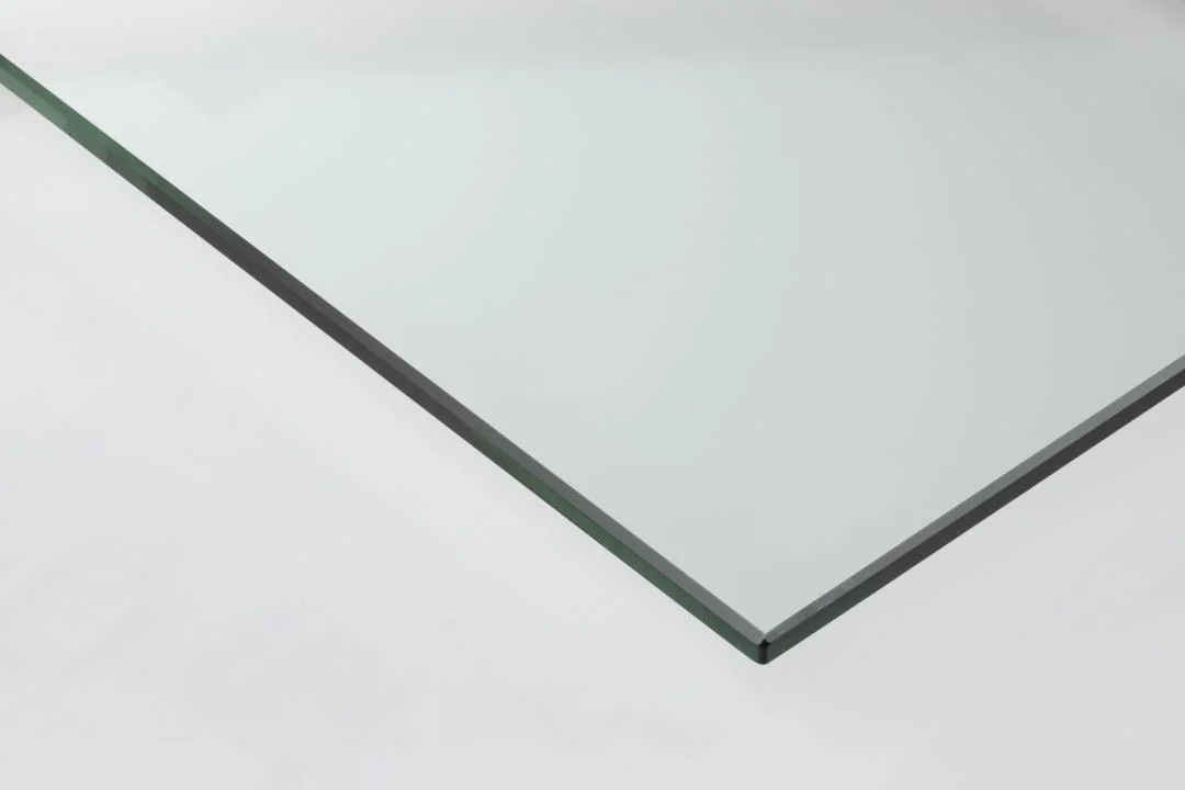 Een close-up van de Salontafel Transparant Rechthoek Glas, een rechthoekig helder glasblad met gladde randen op een wit oppervlak, dat het dunne profiel en de transparantie benadrukt.