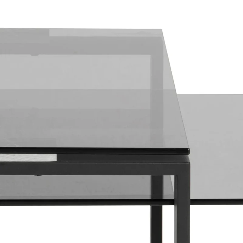 Close-up van de Salontafel Rookglas, Zwart (40 x 45 CM), met een rechthoekig blad van gerookt glas en een zwart metalen frame met strakke lijnen en geometrische vormen, tegen een witte achtergrond.