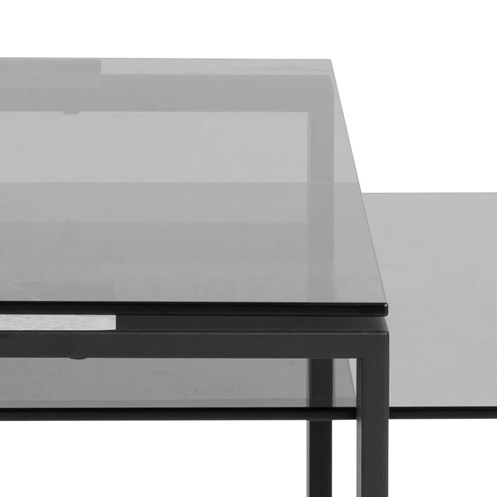 Close-up van de Salontafel Rookglas, Zwart (40 x 45 CM), met een rechthoekig blad van gerookt glas en een zwart metalen frame met strakke lijnen en geometrische vormen, tegen een witte achtergrond.
