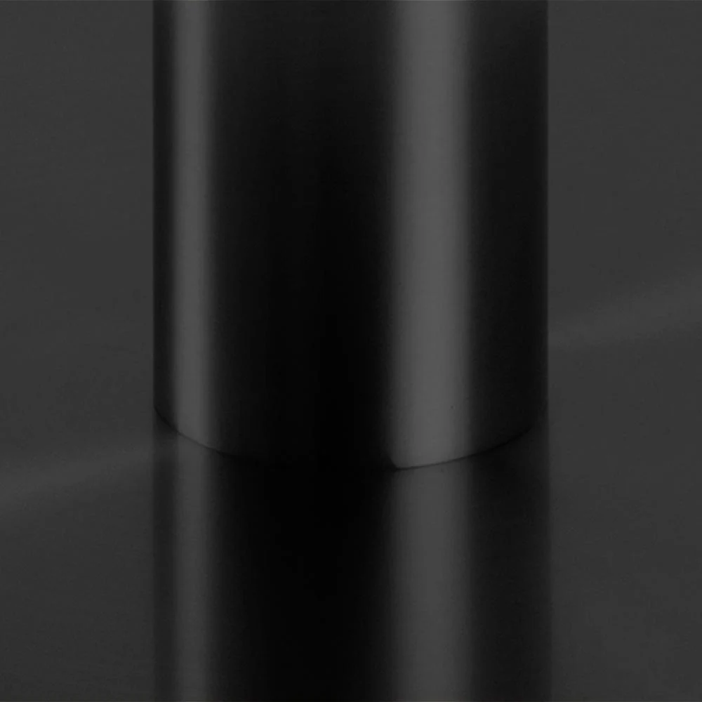 Een close-up van de matzwarte basis van de Eettafel Nieuwe Sfeer 105 CM Rond Marmer op een reflecterend zwart oppervlak, dat het gladde cilindrische ontwerp en de minimalistische stijl benadrukt.