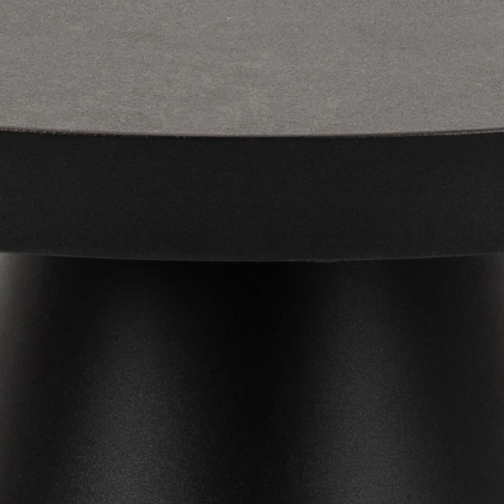 Close-up van de Salontafel Zwart 45 CM Rond Keramiek: heeft een matzwarte cilindrische voet en een glad, donkergrijs tafelblad van keramiek. Het minimalistische, moderne ontwerp wordt benadrukt door de focus op de rand en de basis.