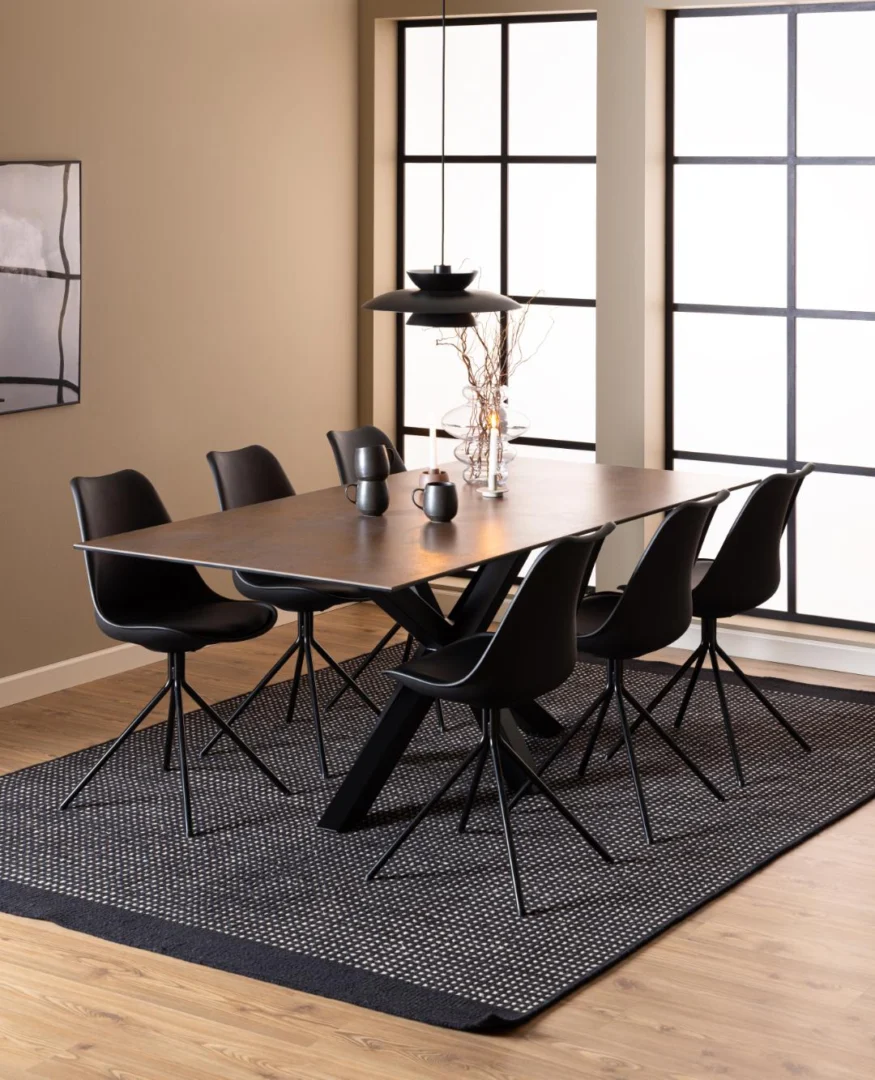 Moderne eetkamer met de Eettafel Nieuwe Sfeer 200 x 100 CM, een rechthoekige tafel van keramiek, zes zwarte stoelen, zwarte hanglamp, minimalistische inrichting, grote rasterramen, beige muren, houten vloer en een zwart vloerkleed met structuur.