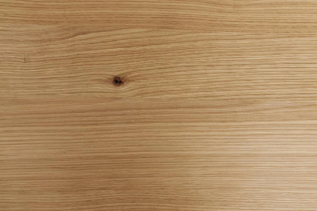 De Eettafel Hemel 220 x 100 CM Rond heeft een lichtbruin eikenhouten oppervlak met natuurlijke nerfpatronen en een donkere knoest aan de linkerkant, wat een eenvoudige, rustieke uitstraling geeft. De tafel combineert eikenhout en staal voor een stijlvol, stevig ontwerp.