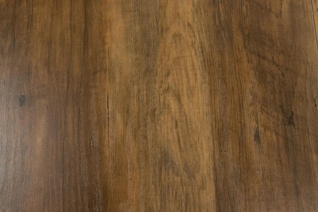 Close-up van de Eettafel Zalida 120 CM Rond Eikenhout. Het gladde eiken oppervlak met natuurlijke nerf, warme aardetinten en subtiele textuur. Voorzien van een stevige, uitschuifbare stalen voet voor extra veelzijdigheid.