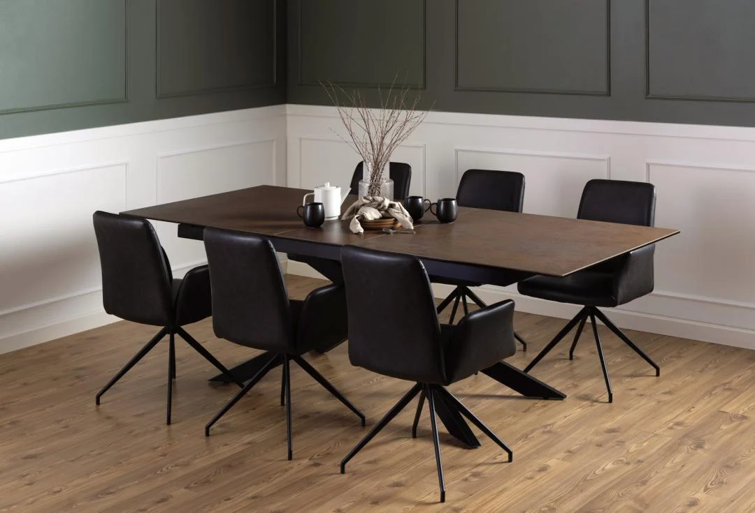 Een moderne eetkamer is voorzien van de Eettafel Nieuwe Sfeer 240 x 100 CM, een rechthoekige tafel met glas en staal, zes zwarte draaistoelen, decoratieve takken in een vaas, kaarsen, mokken, groen en wit gelambriseerde muren en een houten vloer.