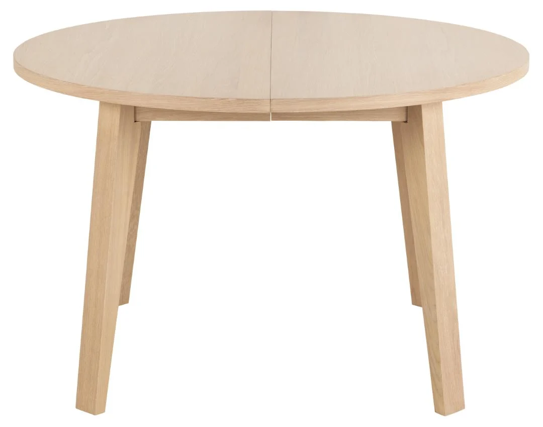 De Eettafel 120 CM Rond Spaanplaat is een ronde houten tafel met een lichte afwerking, vier schuine poten en een zichtbare naad in het midden van het tafelblad.