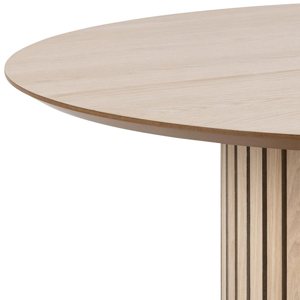 Close-up van de Eettafel Nieuwe Sfeer 120 CM Rond, met een licht afgewerkt rond eiken tafelblad en een cilindervormig onderstel met verticale latten. Slechts een deel van de eikenhouten tafel en het onderstel is zichtbaar.